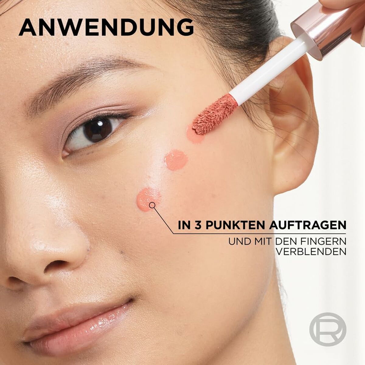 Application of liquid makeup on a model's face with instructions for blending with fingers.