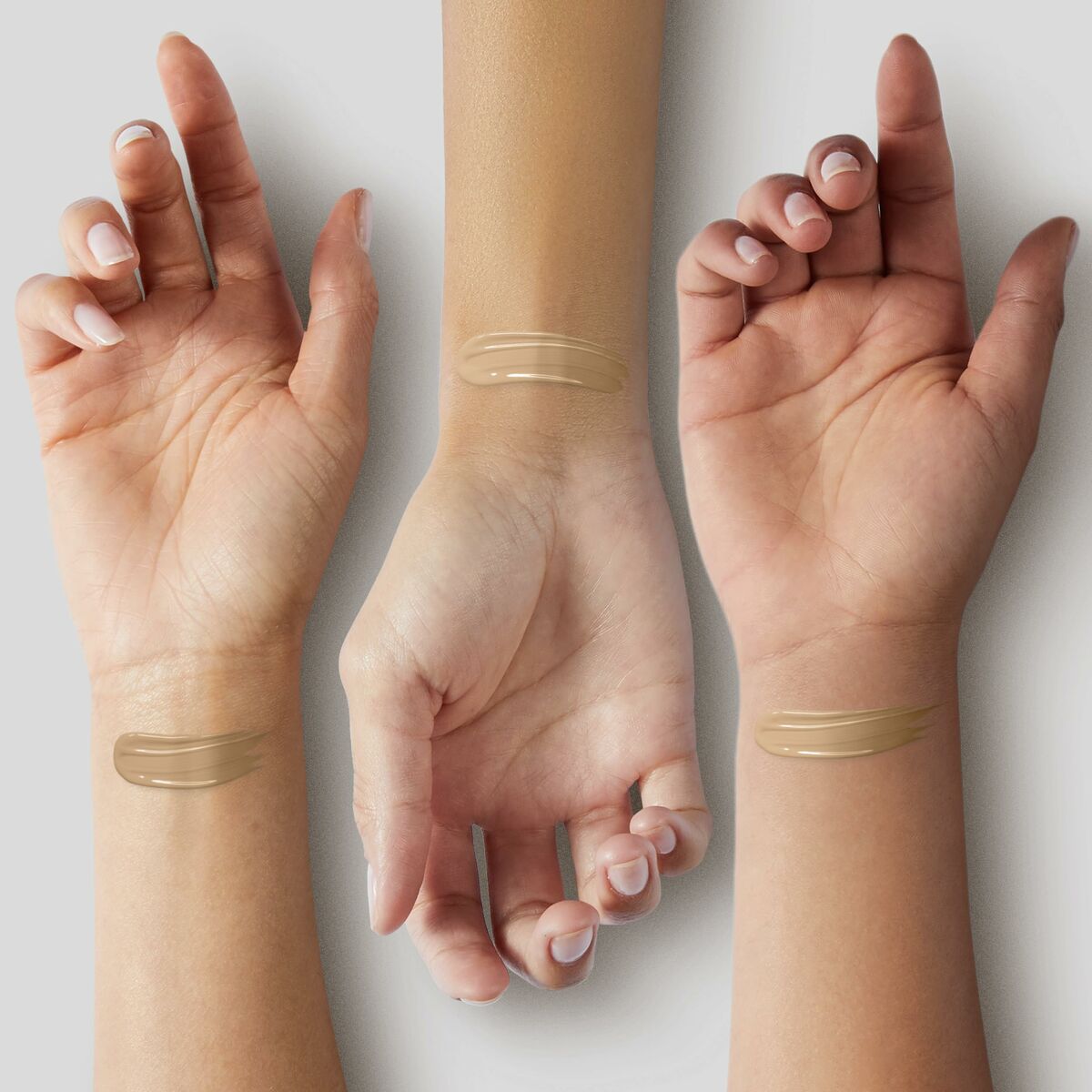 Trois bras avec des échantillons de base de maquillage liquide Estee Lauder, montrant différentes teintes sur la peau.