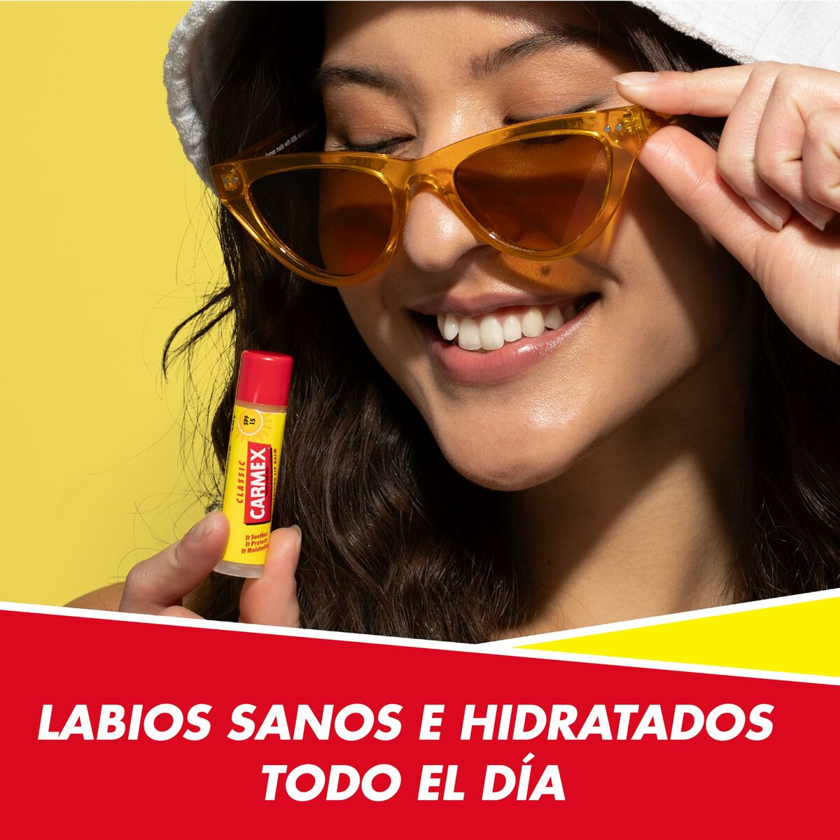 Femme souriante tenant un stick de baume à lèvres Carmex sous le soleil, mettant en avant des lèvres hydratées.