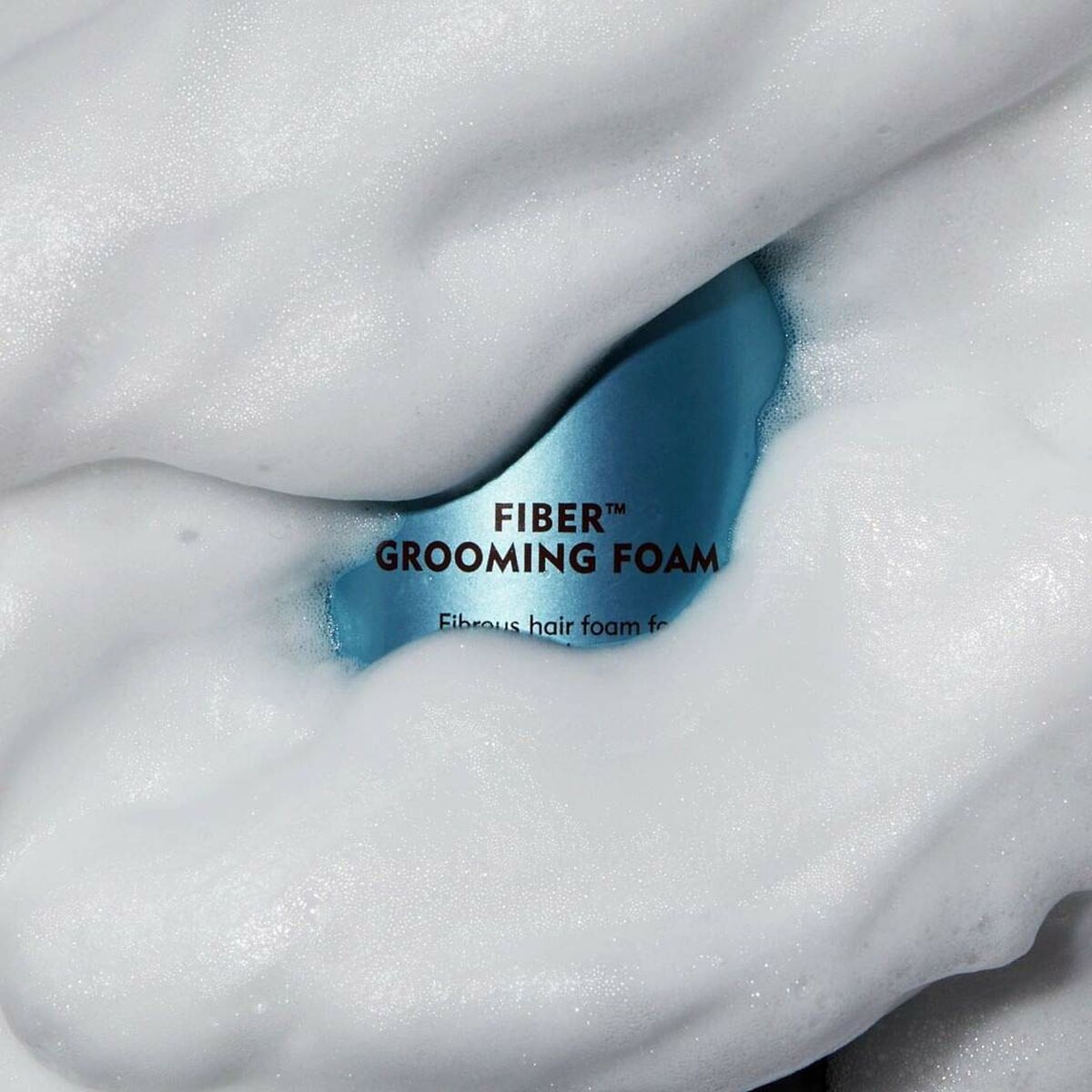 American Crew Fiber Grooming Foam surrounded by rich, fluffy foam for textured styling.