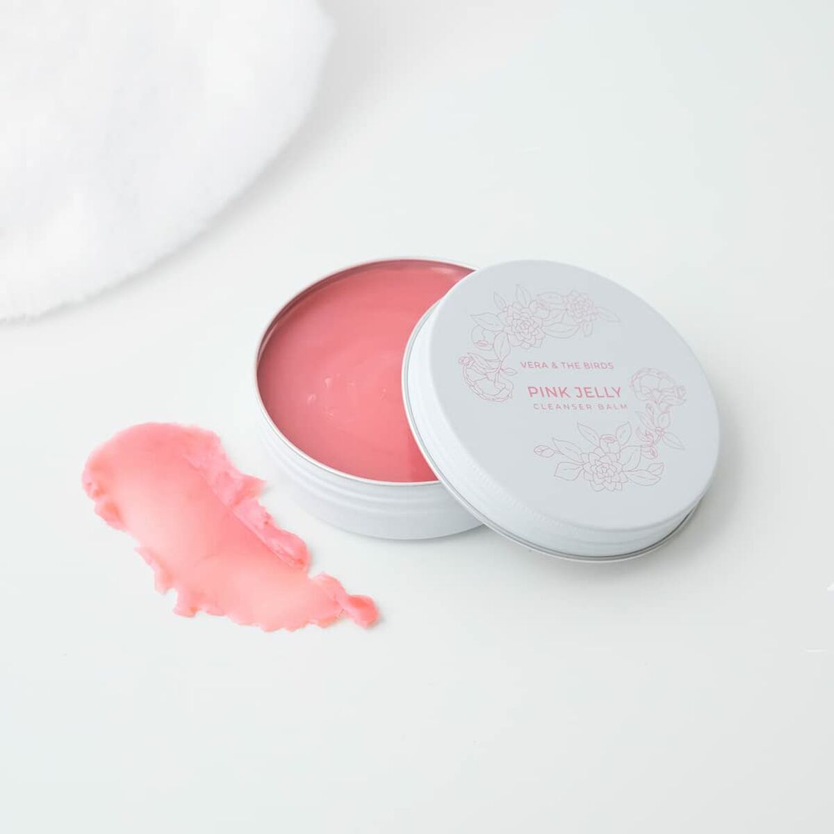 Pink Jelly skincare product in a silver tin with a pink cream beside it on a white background.