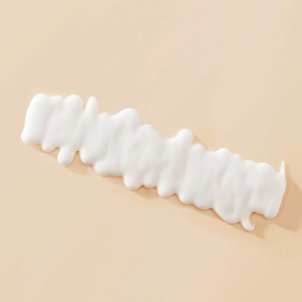 Texture of Living Proof Curl defining fluid on a beige surface, showcasing its creamy consistency for hair styling.