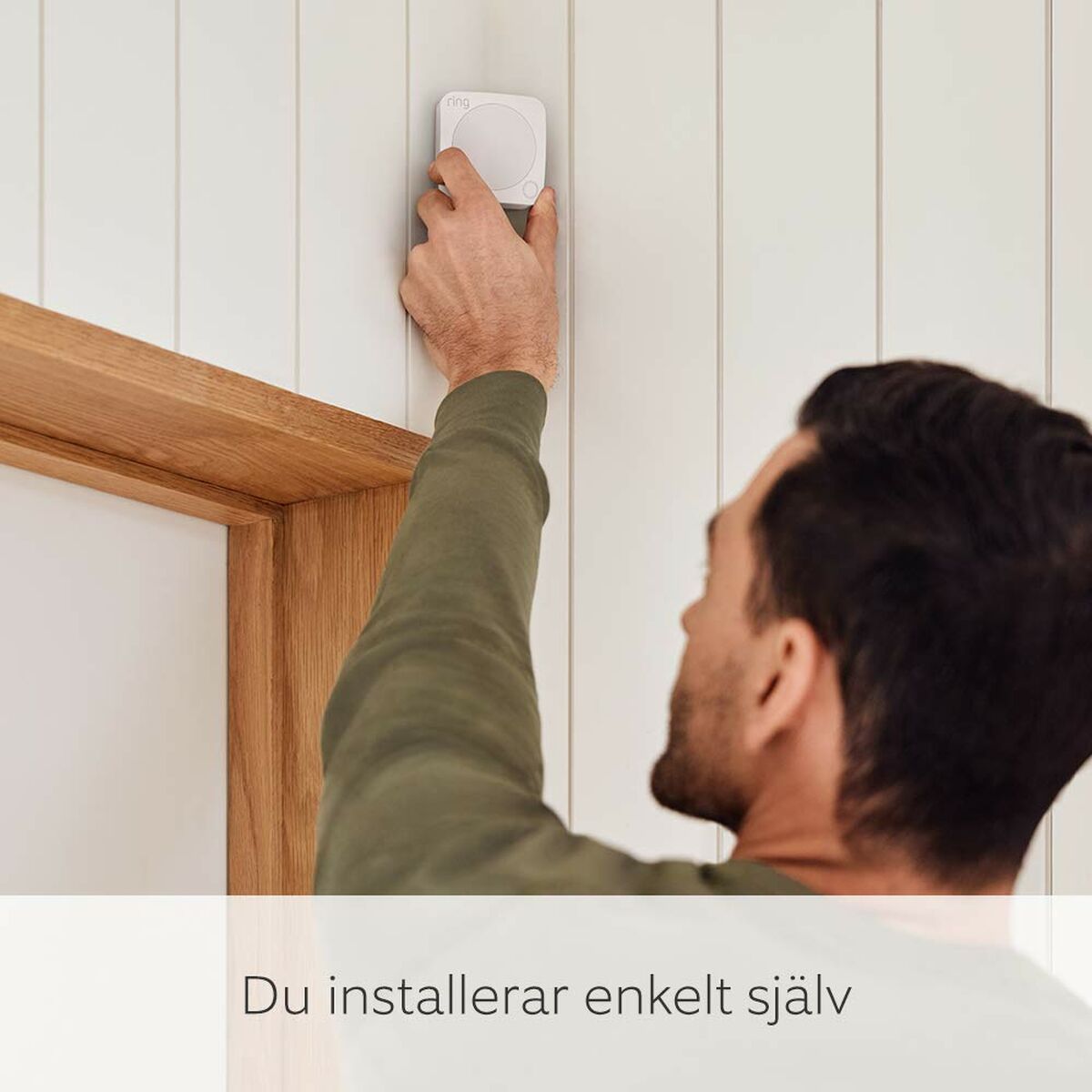 Homme installant le système de sécurité Amazon B08L5TWL9D blanc sur un mur, facile à installer soi-même.