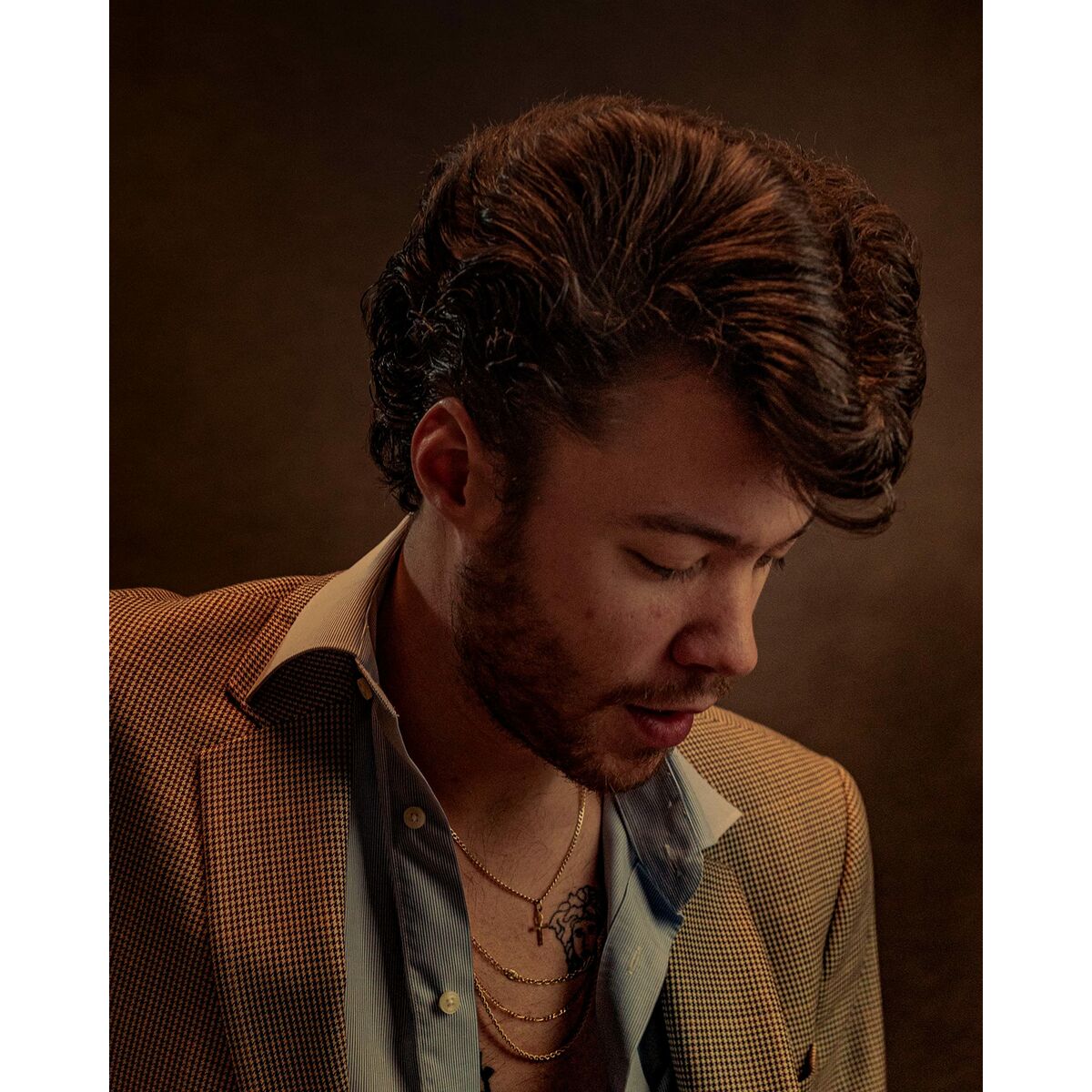 Stylish male portrait with textured hair, wearing a blazer, captured in soft light for a sophisticated look.