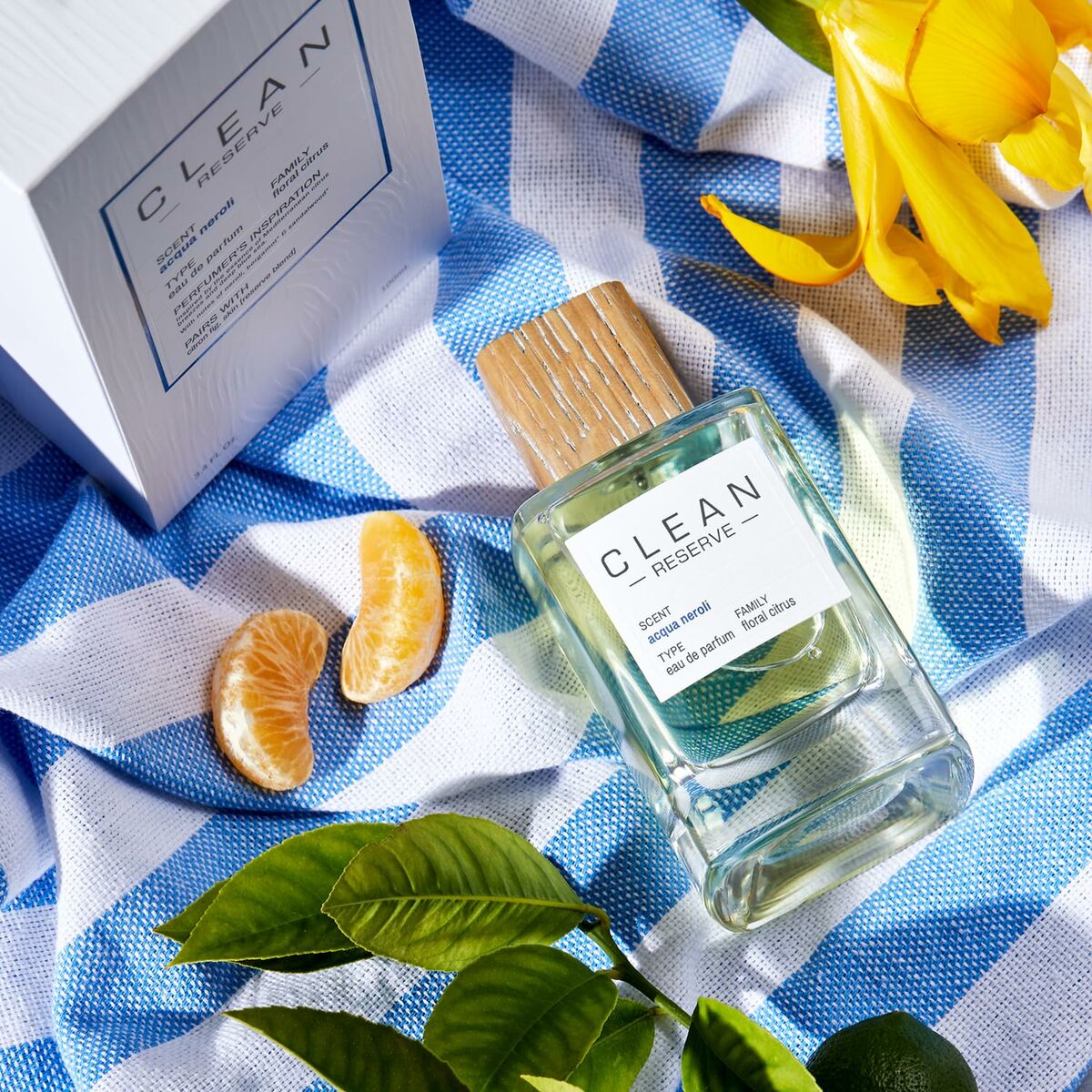Parfum Femme Clean EDP presented on a blue checkered cloth with citrus and floral accents, highlighting its feminine allure.
