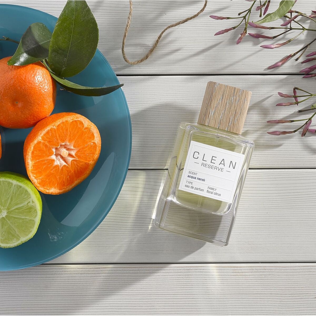 Clean Reserve EDP bottle beside fresh citrus fruits on a blue plate, highlighting a refreshing fragrance experience.