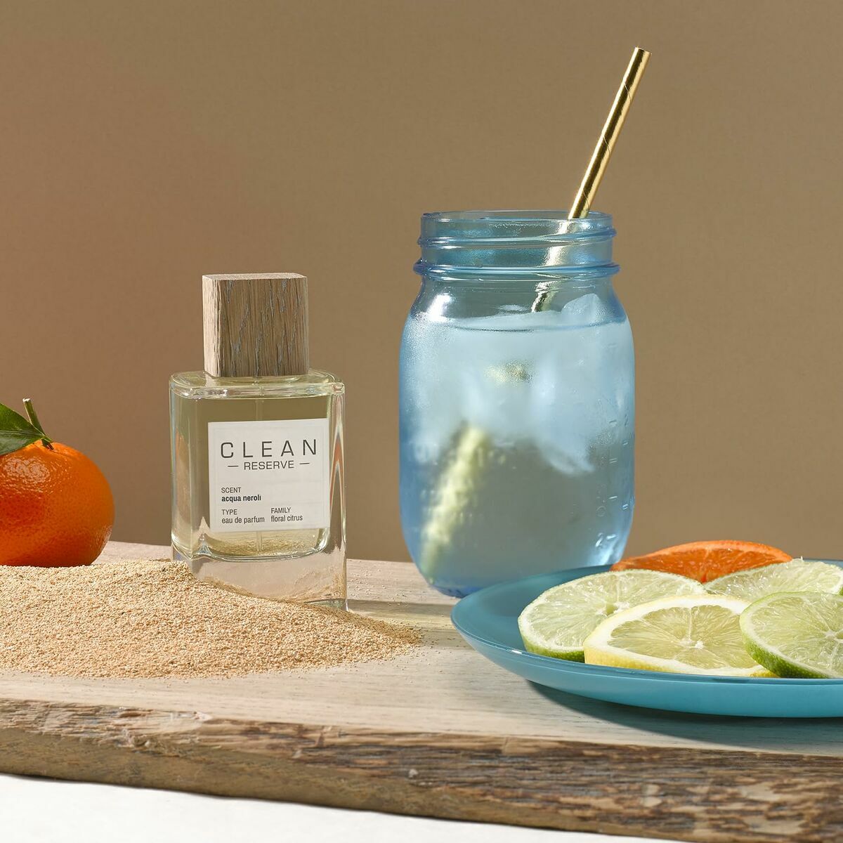 Parfum Femme Clean EDP bottle with citrus fruits and refreshing drink on a wooden tray.