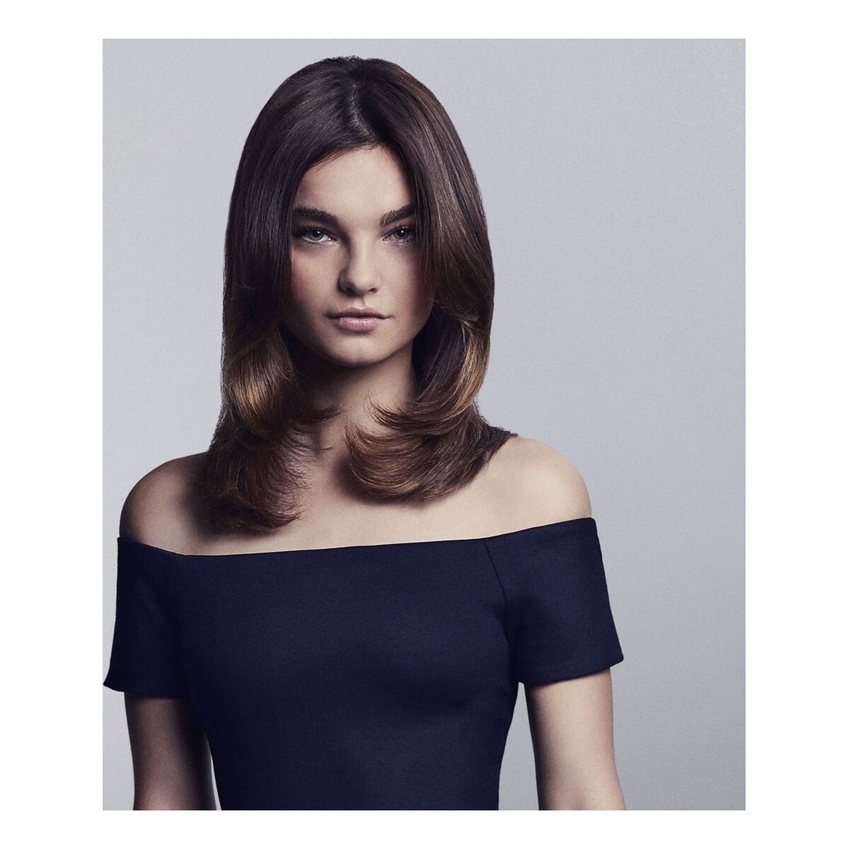 Femme avec cheveux lisses et brillants, portant un haut noir, mettant en valeur le style moderne et chic.