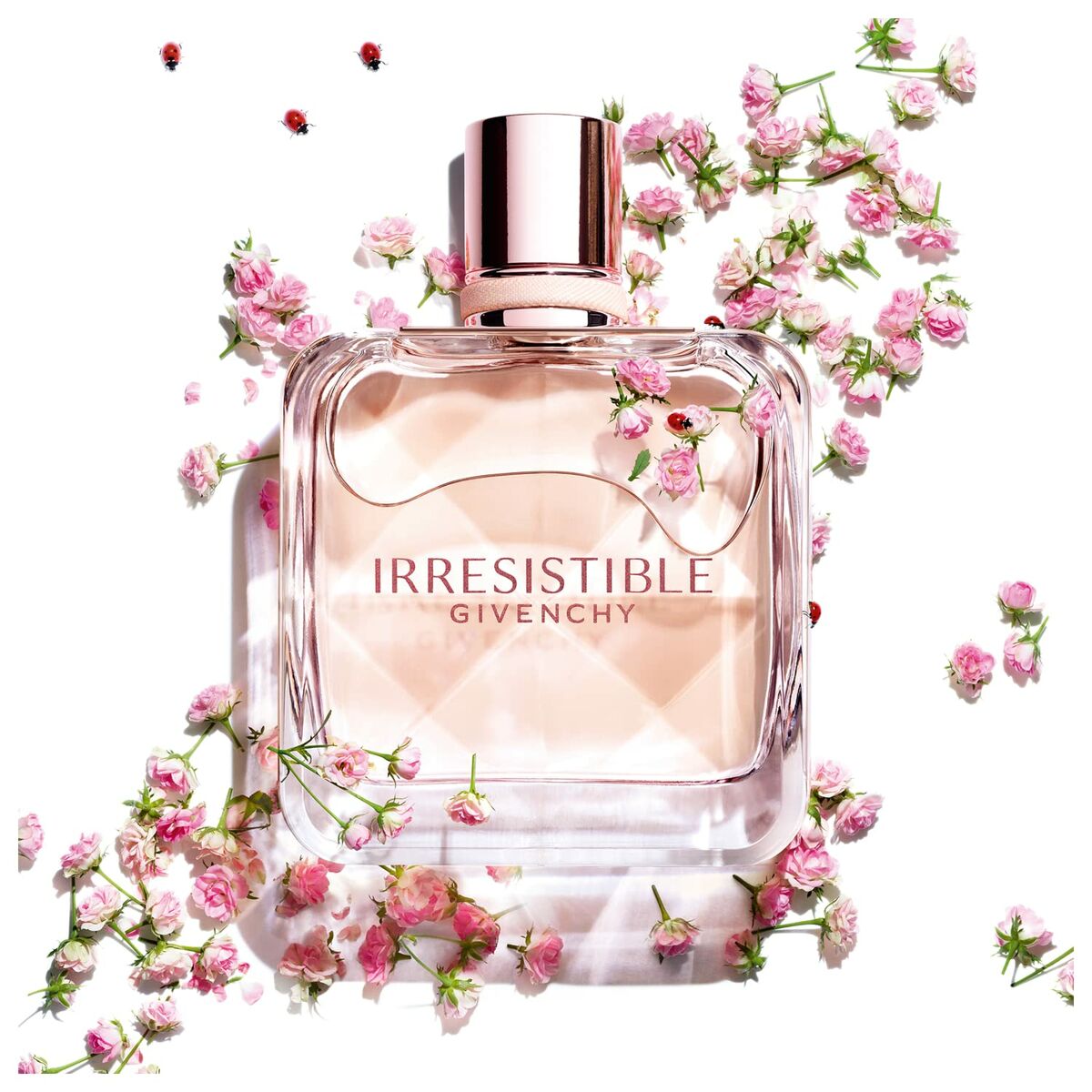 Givenchy Irresistible EDT 50ml perfume bottle surrounded by pink flowers, showcasing its elegant design and floral essence.