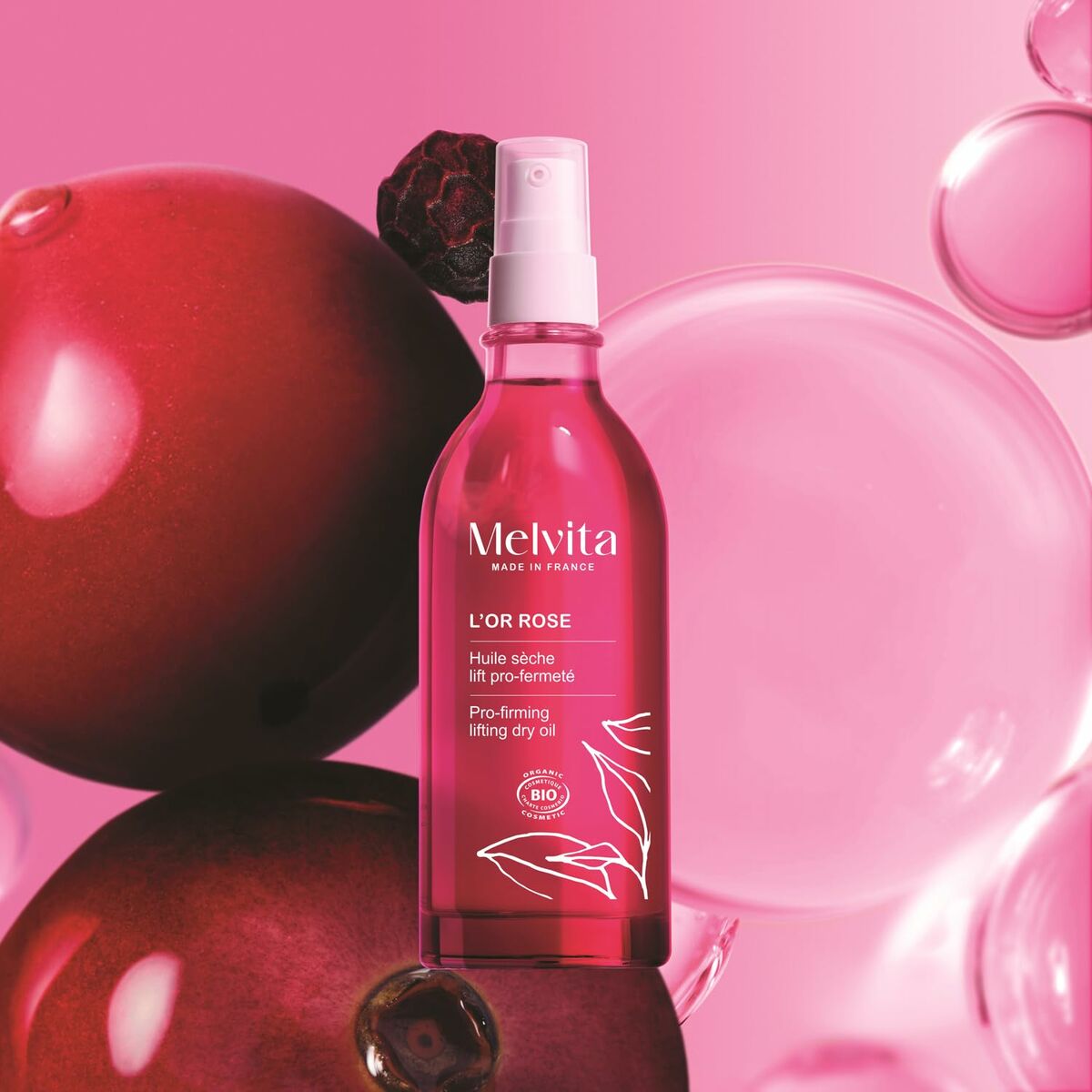 Lotion corporelle Melvita L'OR ROSE in a pink setting with bubbles and fruit, promoting skin firmness and hydration.