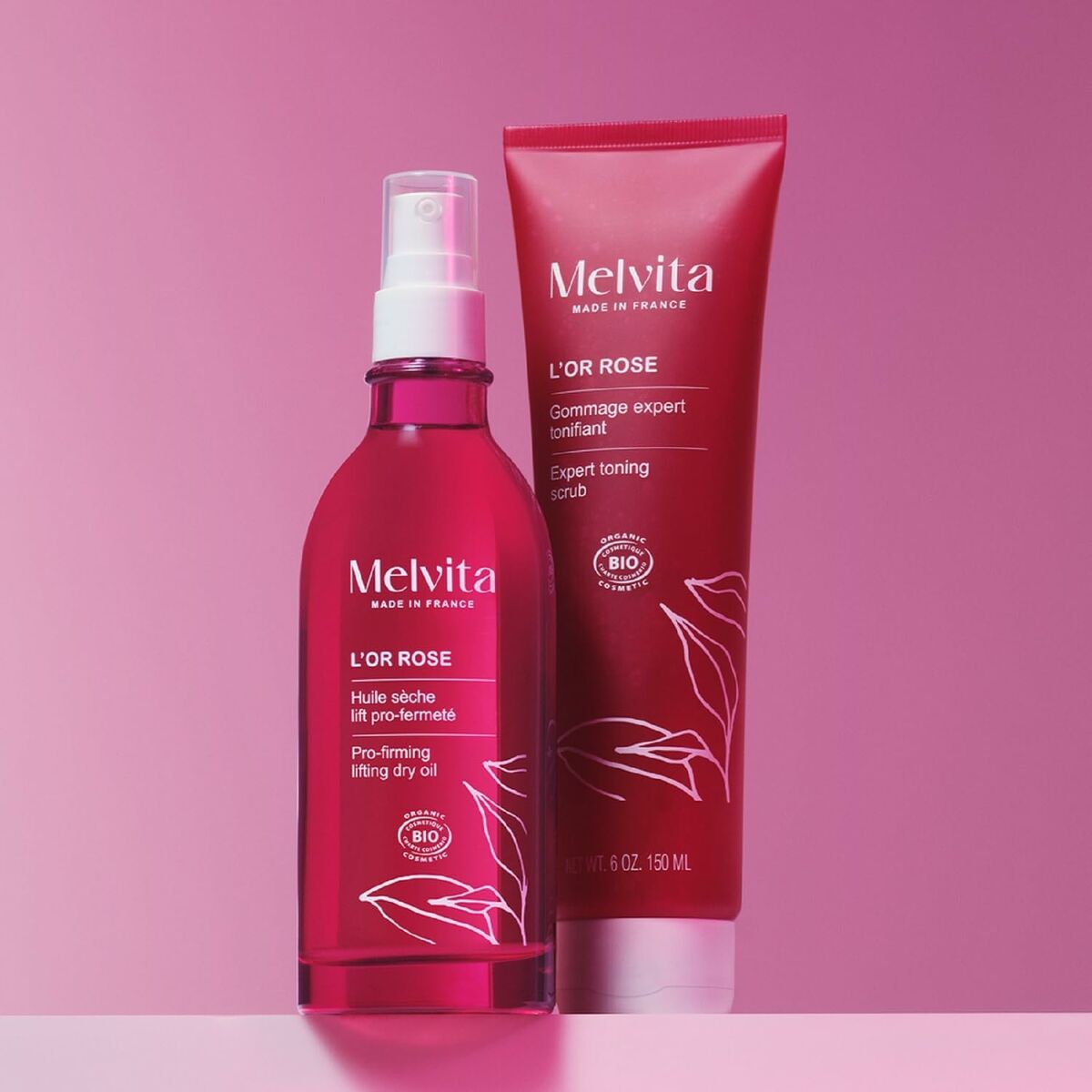 Lotion corporelle Melvita L'OR ROSE and expert toning scrub on pink background, featuring organic beauty products.