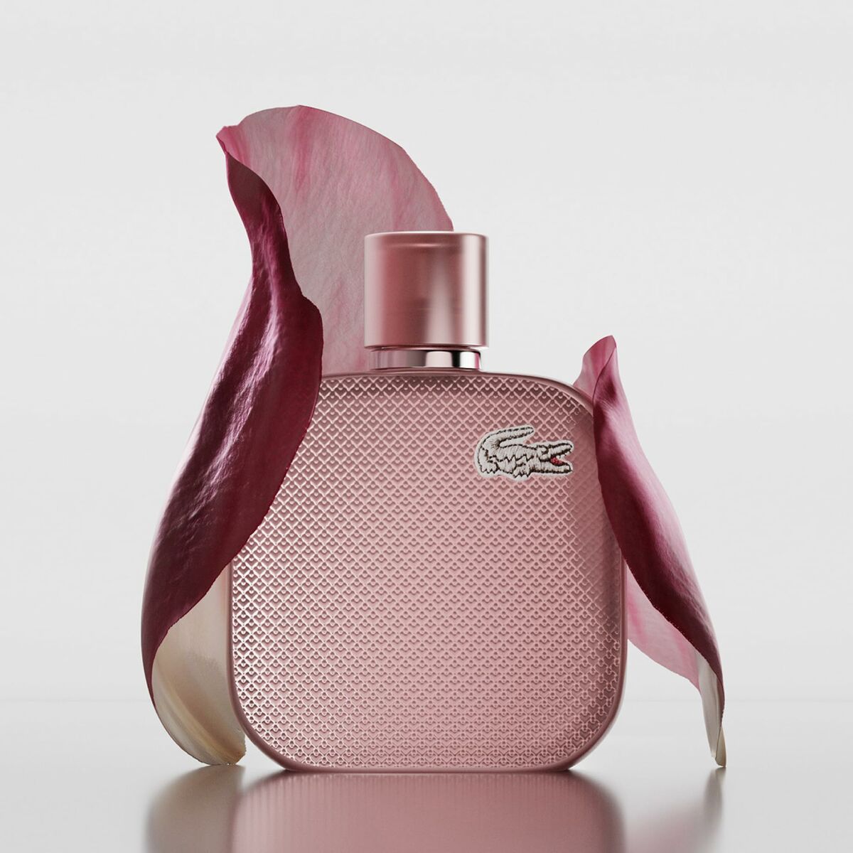Parfum Femme Lacoste L.12.12 POUR ELLE in a pink bottle surrounded by rose petals.