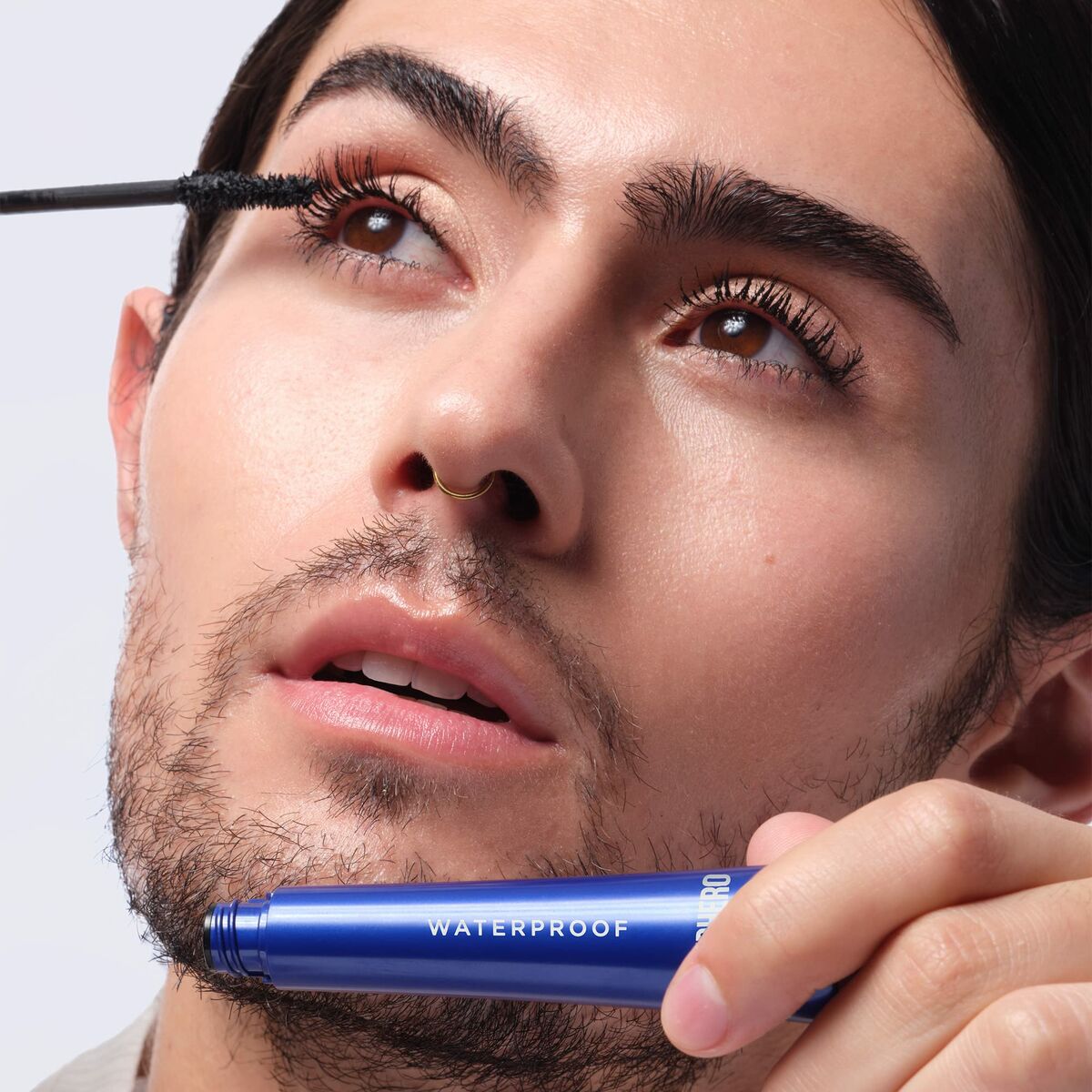 Person applying waterproof mascara for flawless eye makeup look.