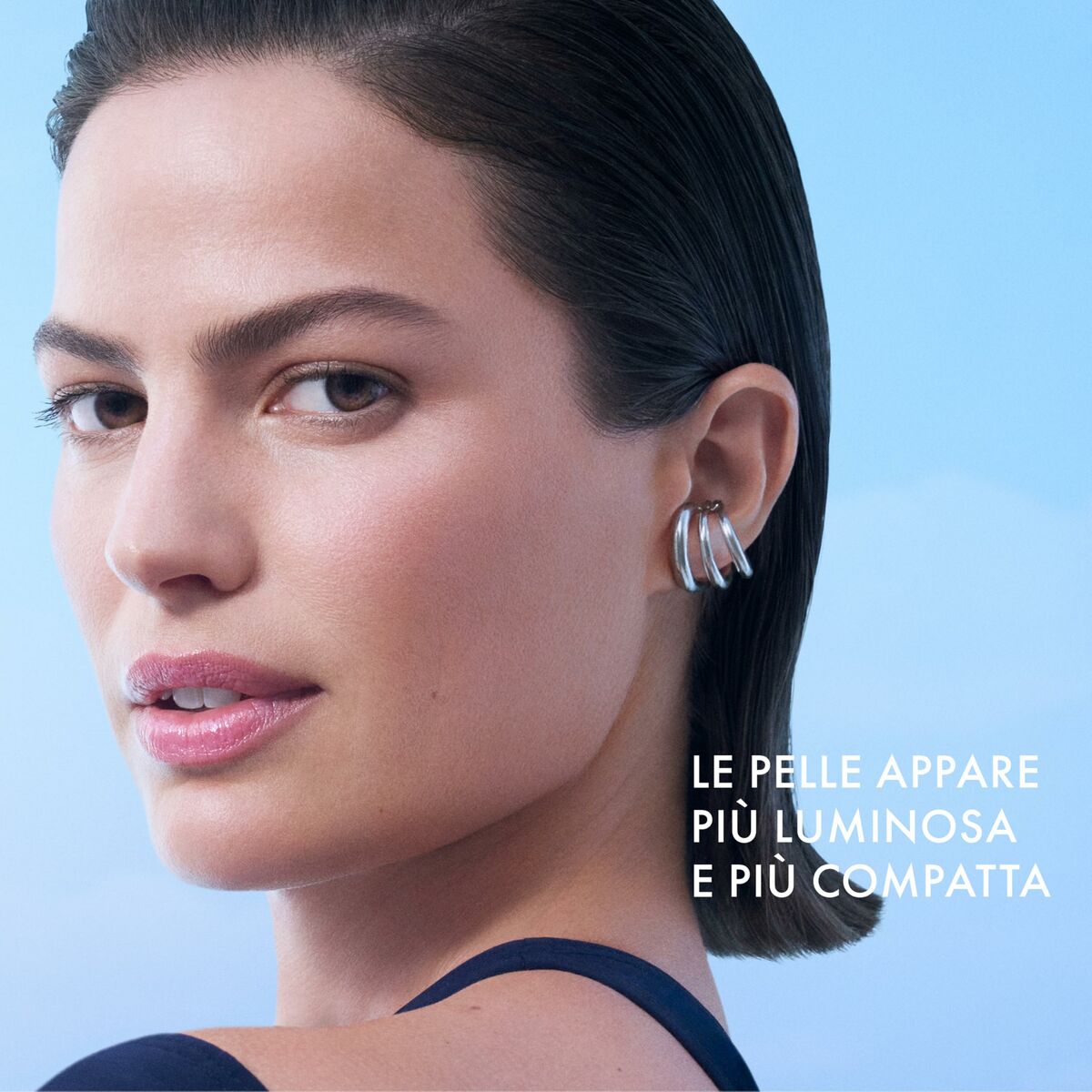 Close-up of a woman with glowing skin, wearing stylish earrings, promoting skin care benefits.