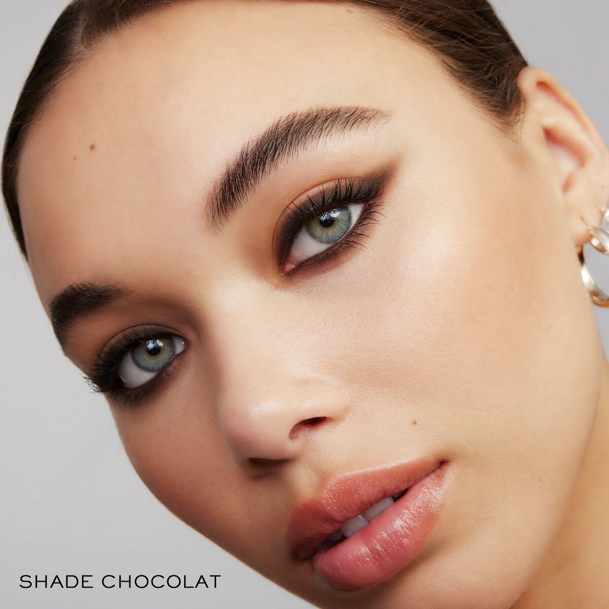 Close-up of a model showcasing makeup in shade Chocolat, highlighting eyes and lips for a stunning beauty look.