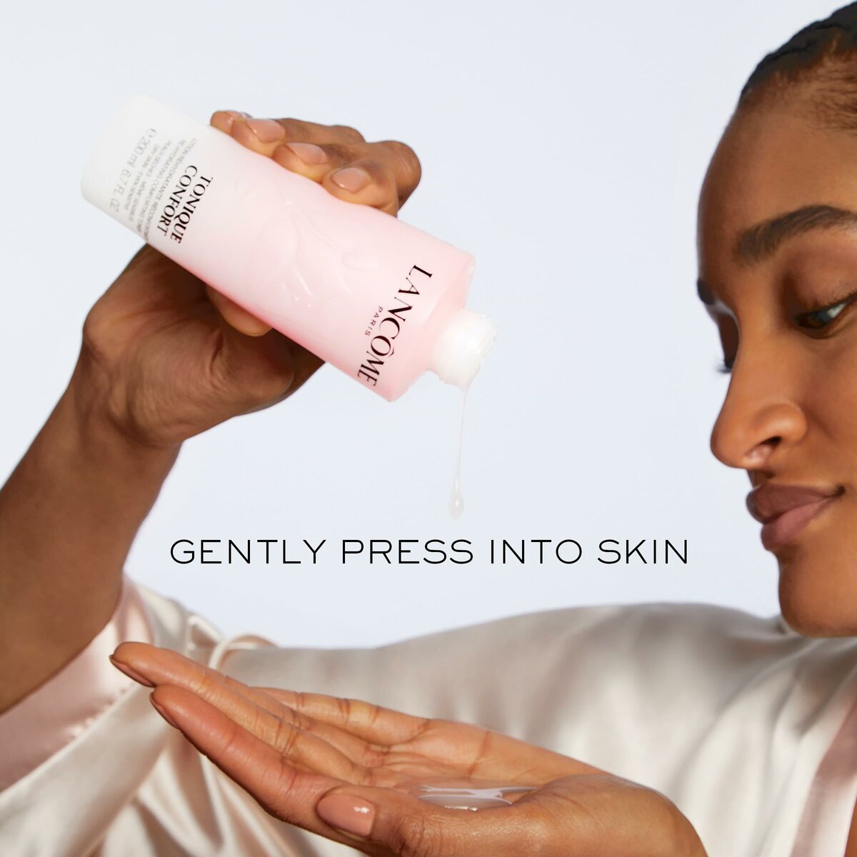 Woman applying Lancôme Gel nettoyant visage CONFORT onto her hand for skincare routine.