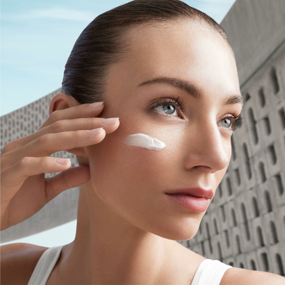 Model applying Biotherm AQUASOURCE cream on her face, showcasing beauty and skincare routine.