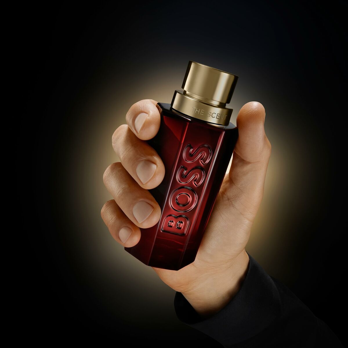 Main image of Hugo Boss The Scent men's perfume in a hand, showcasing its stylish red bottle design.