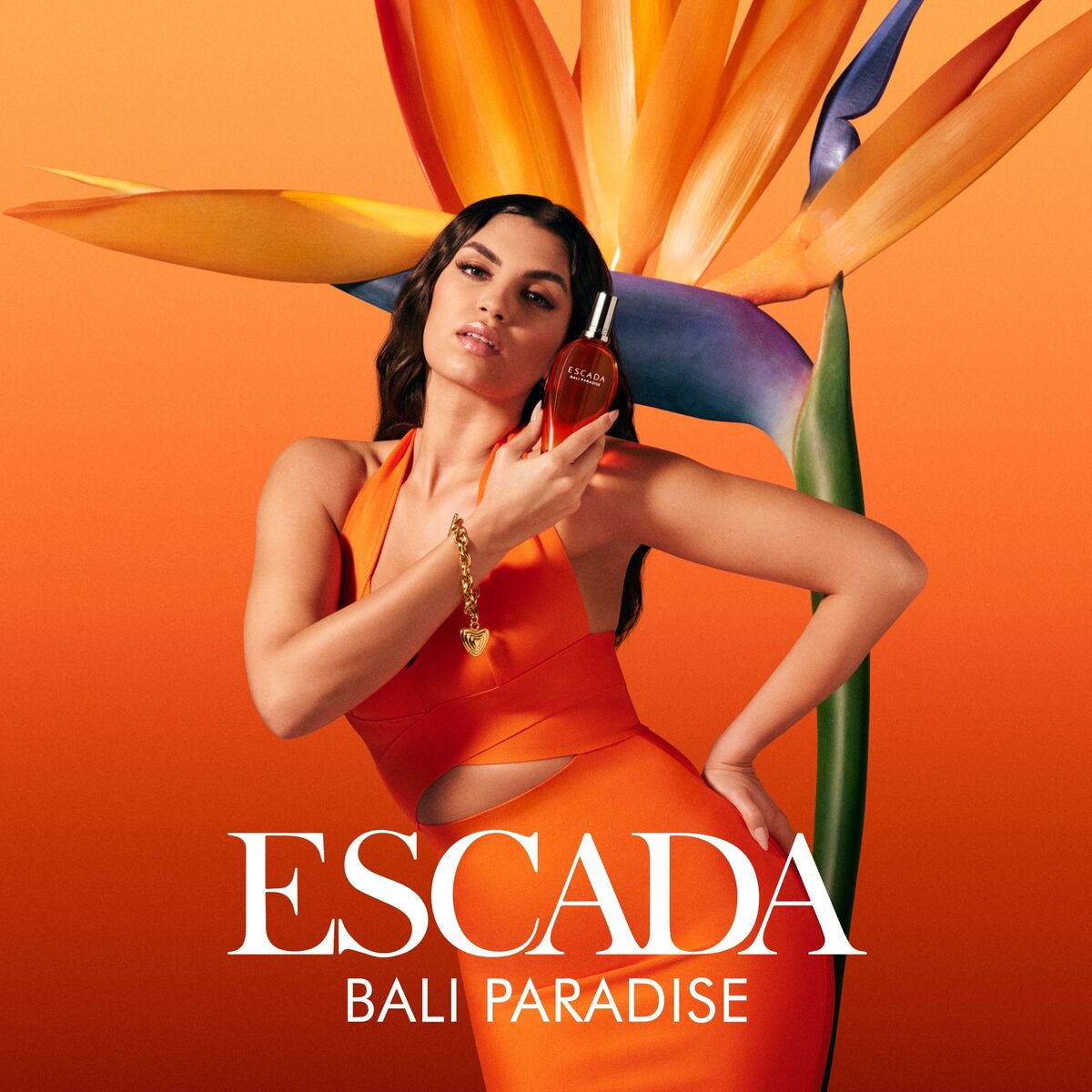 Escada Bali Paradise parfum for women, 100ml, model holding fragrance in vibrant orange setting with tropical flower.