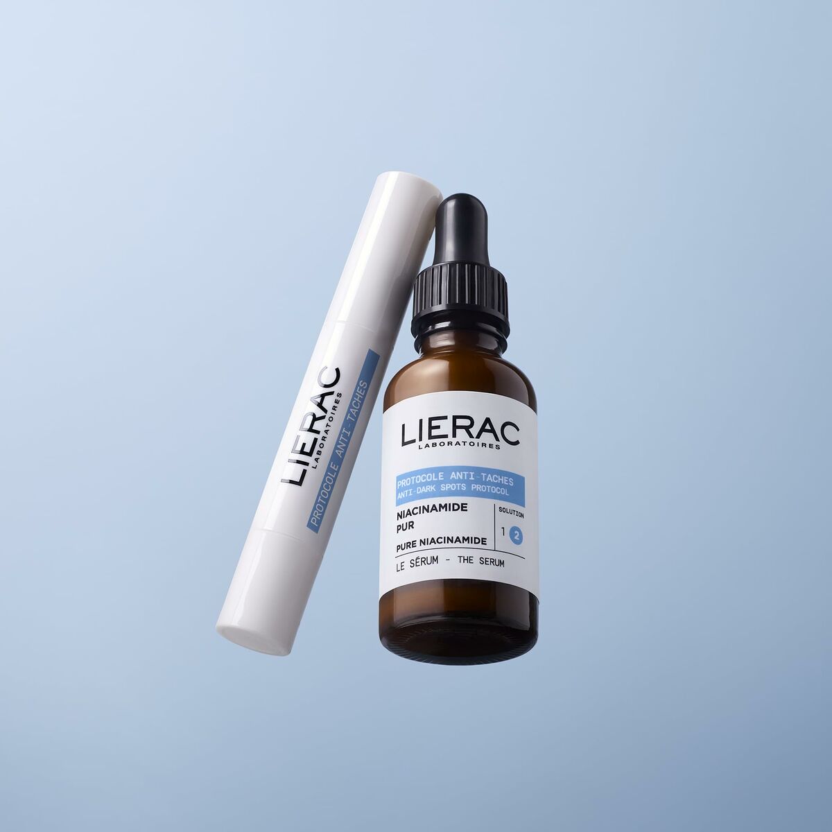 Sérum visage Lierac au niacinamide, flacon en verre brun sur fond bleu, soin de la peau de haute qualité.