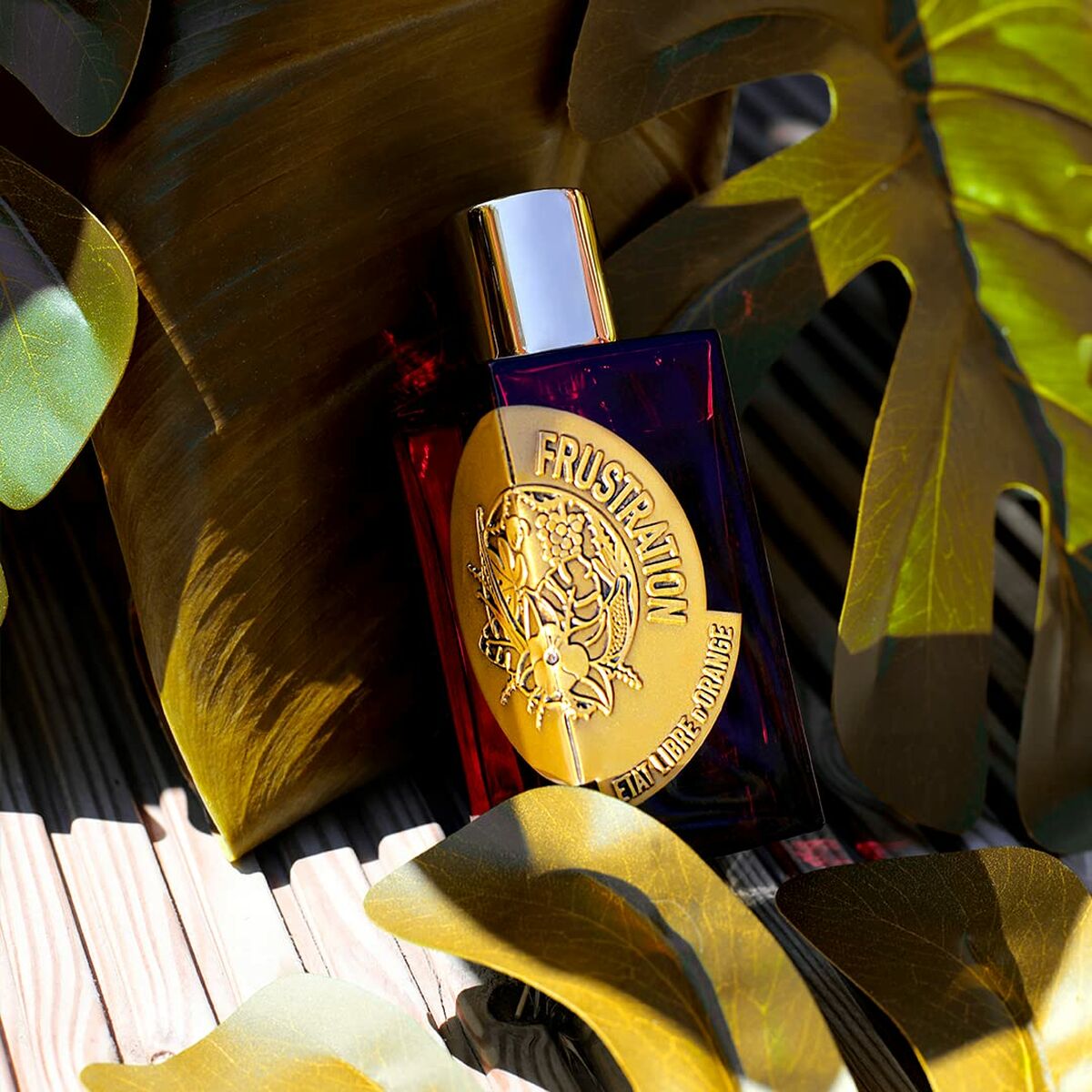 Parfum Femme Etat Libre D'Orange Frustration, EDP 100 ml, sur fond de feuilles tropicales.