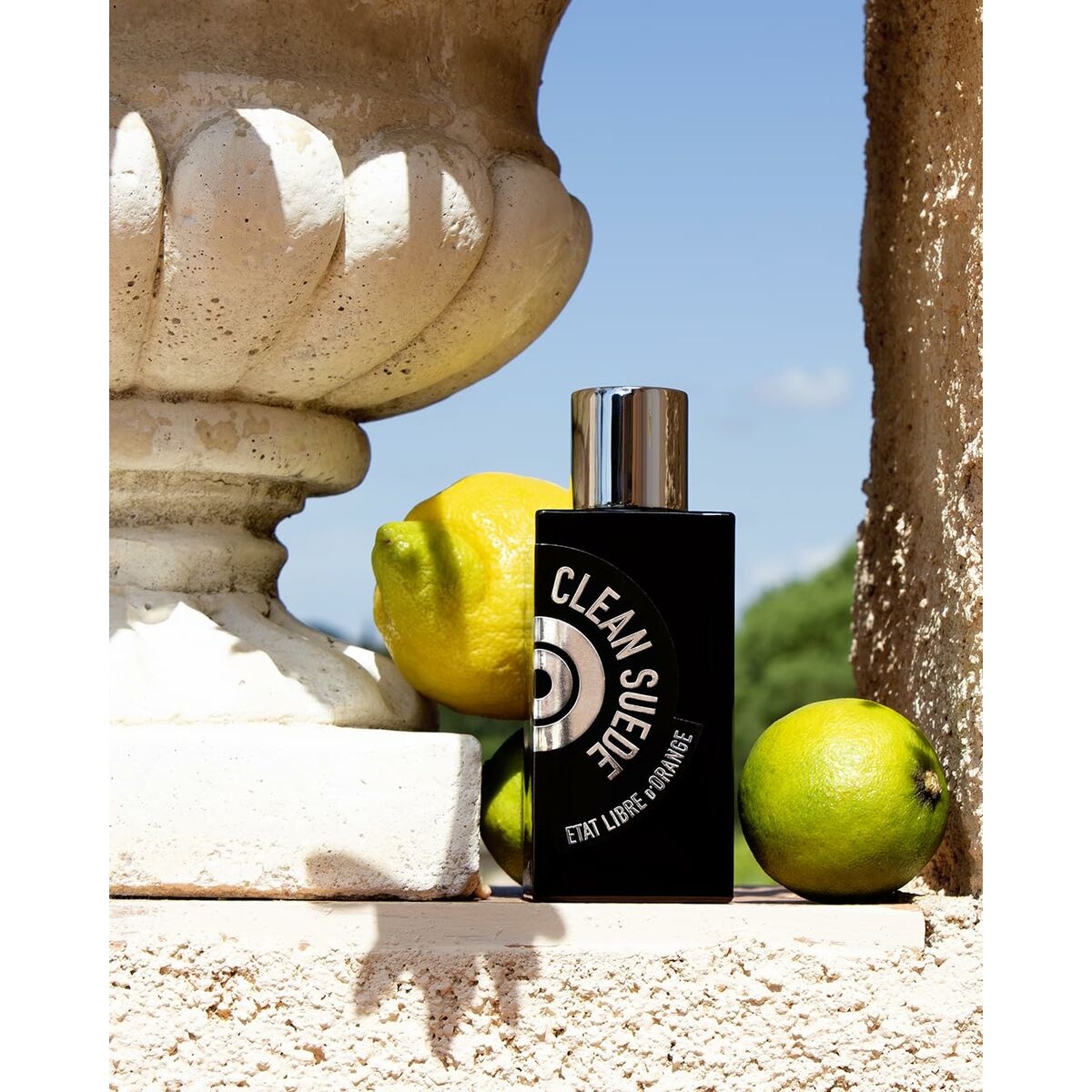Parfum Unisexe Etat Libre D'Orange sur un muret en pierre, entouré de citrons, évoquant fraîcheur et authenticité.