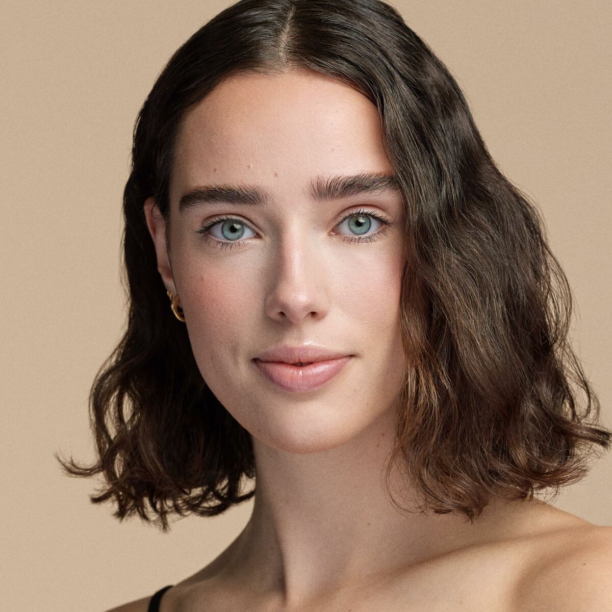 Portrait of a woman with wavy hair and natural makeup showcasing fresh skin and a radiant look.