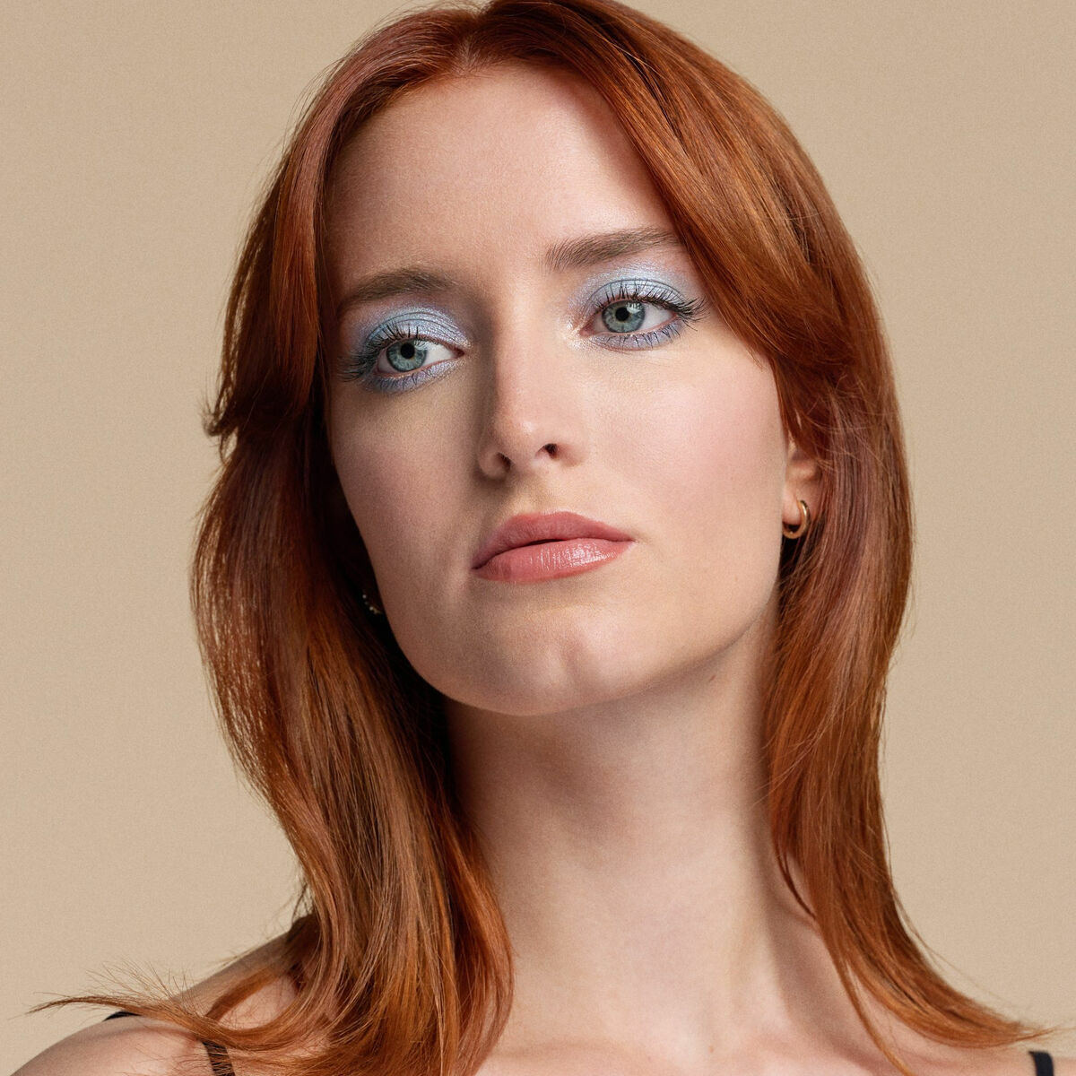 Portrait of a woman with red hair and blue eyeshadow, showcasing a natural beauty look.
