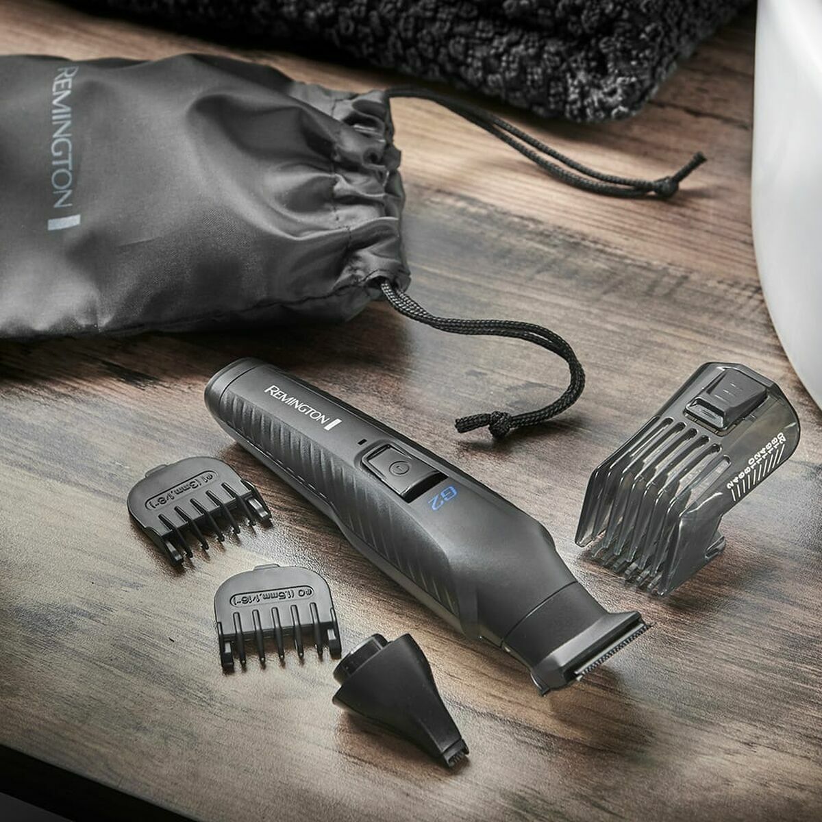 Tondeuse sans fil Remington avec accessoires sur une table en bois, idéale pour le soin personnel à domicile.