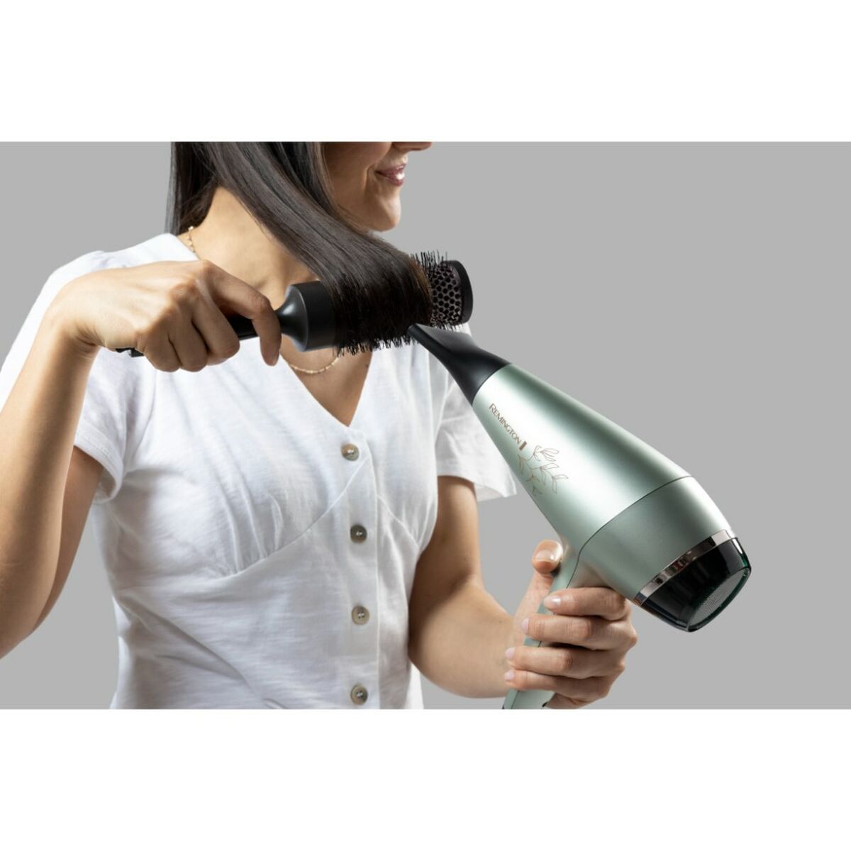 Femme utilisant un sèche-cheveux Remington AC5860 2300 W pour coiffer ses cheveux avec une brosse.