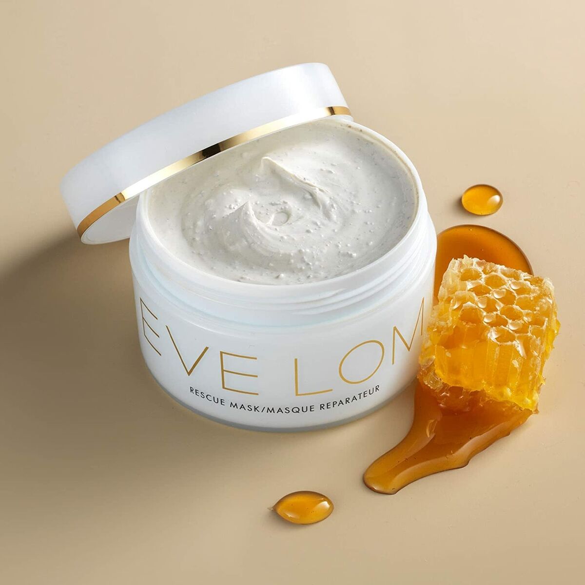 Masque nettoyant et régénérant Eve Lom avec texture crémeuse, pot blanc, miel et propolis sur fond beige.