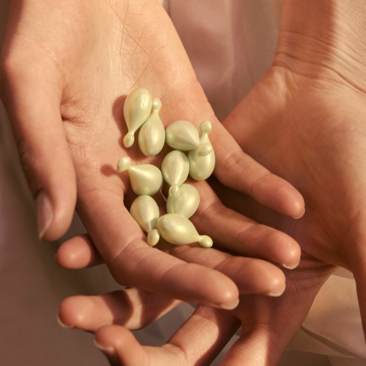 Huile visage Eve Lom capsules in a person's hands, showcasing luxury skincare and beauty care.