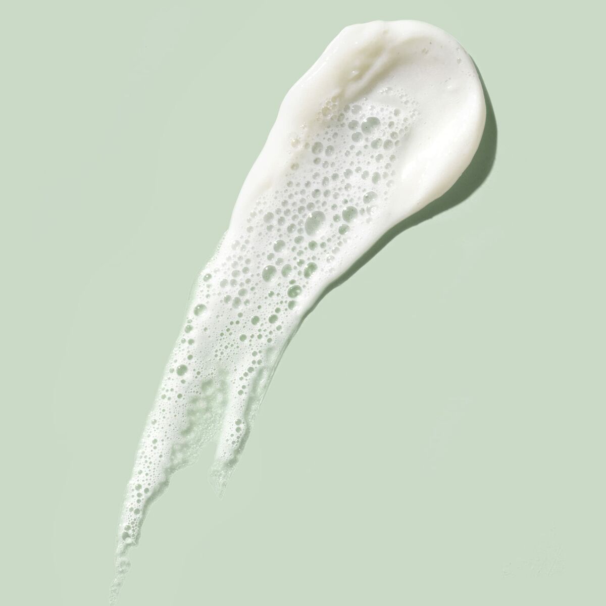 Mousse nettoyante Eve Lom sur fond vert, texture légère et aérée avec des bulles.