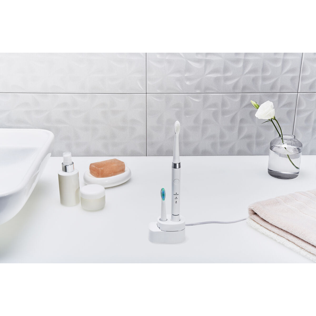 Brosse à dents électrique Panasonic WEW0974W503 sur un meuble de salle de bain, avec accessoires et décorations.