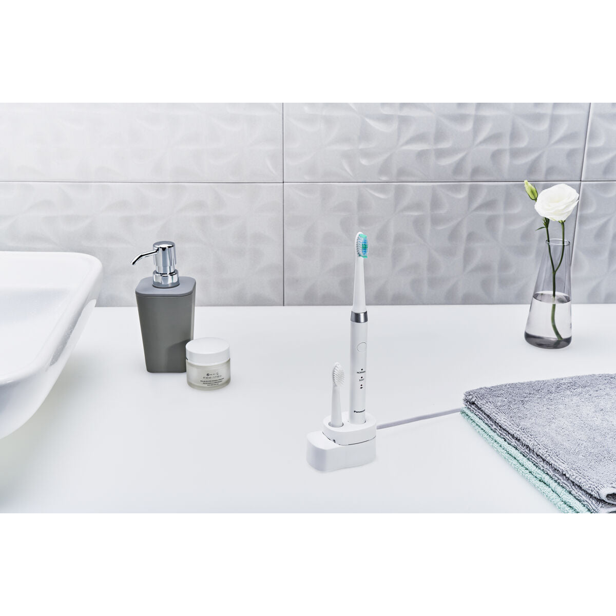Brosse à dents électrique Panasonic WEW0974W503 sur une table de salle de bain avec des produits de soins.