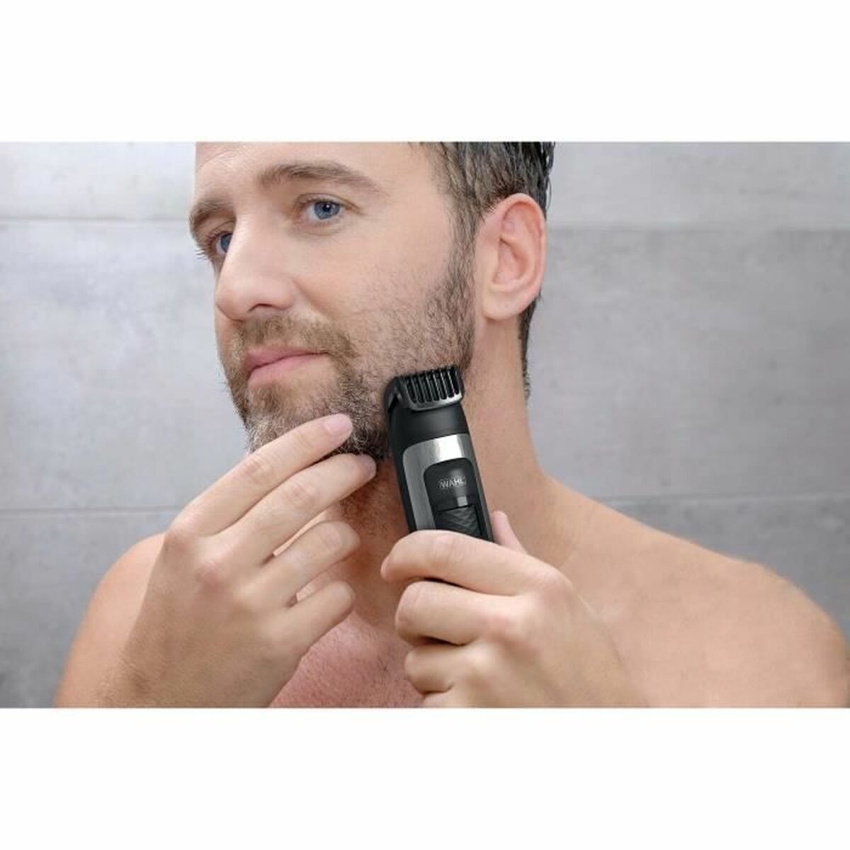 Homme utilisant la tondeuse à cheveux Wahl 1065-0460 pour tailler sa barbe, avec un arrière-plan moderne.