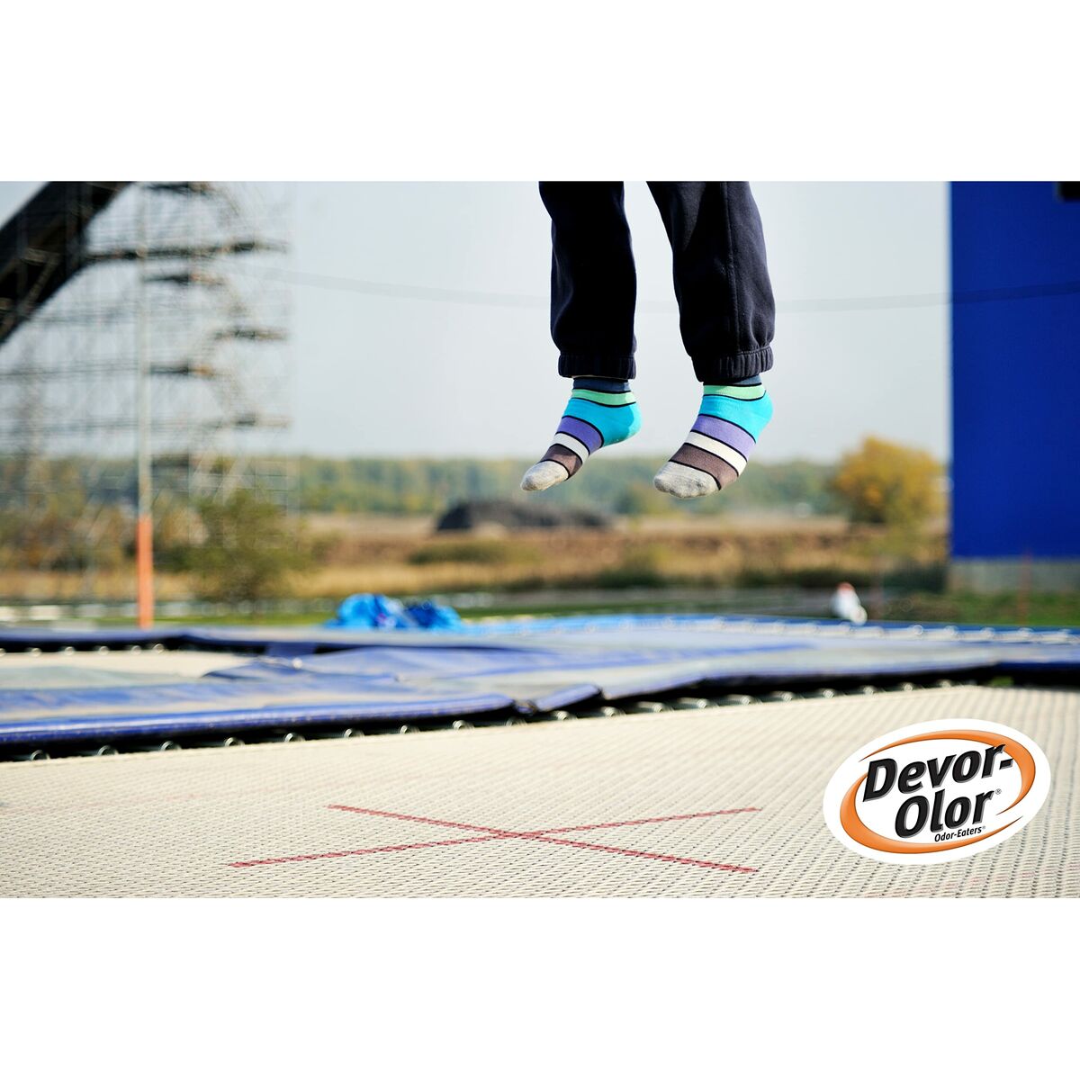 Enfant sautant sur un trampoline avec des chaussettes colorées, logo Devor-Olor en bas à droite.