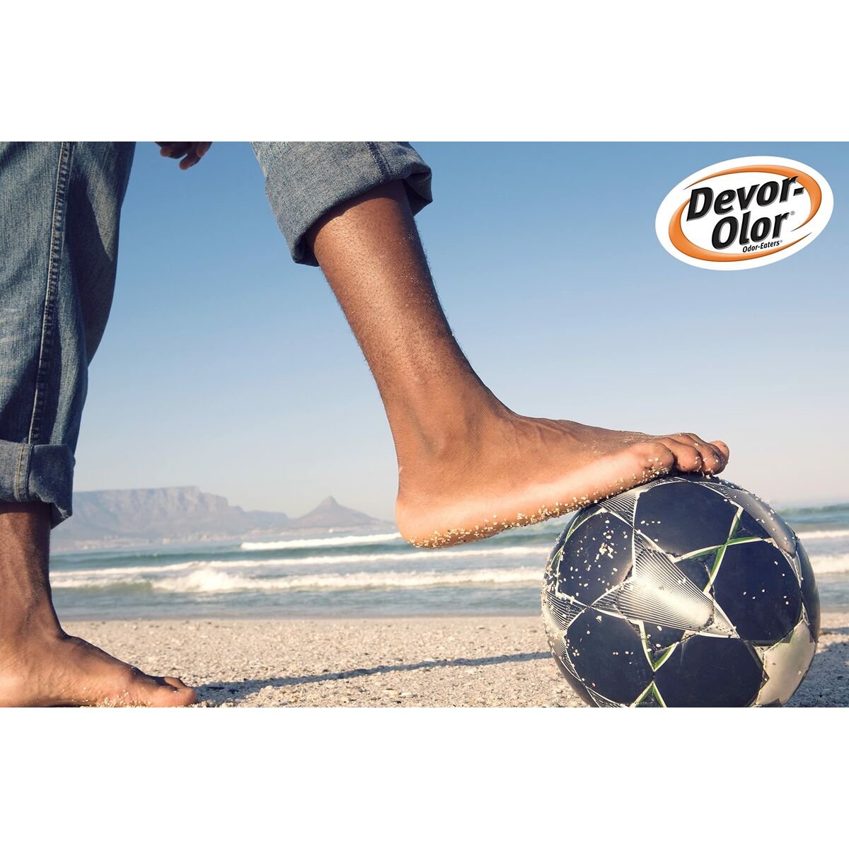 Person playing soccer barefoot on the beach with a Devor-Olor logo in the corner.