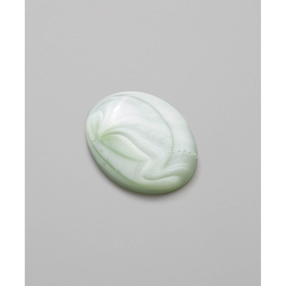 Creamy green ointment with a swirling pattern on a gray background.