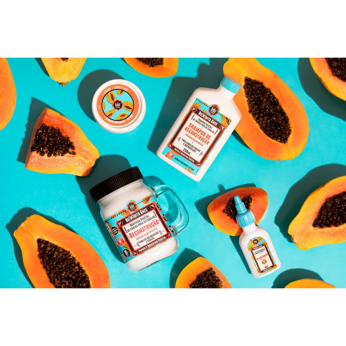 Lola Cosmetics hair care products displayed with fresh papaya on a vibrant turquoise background.