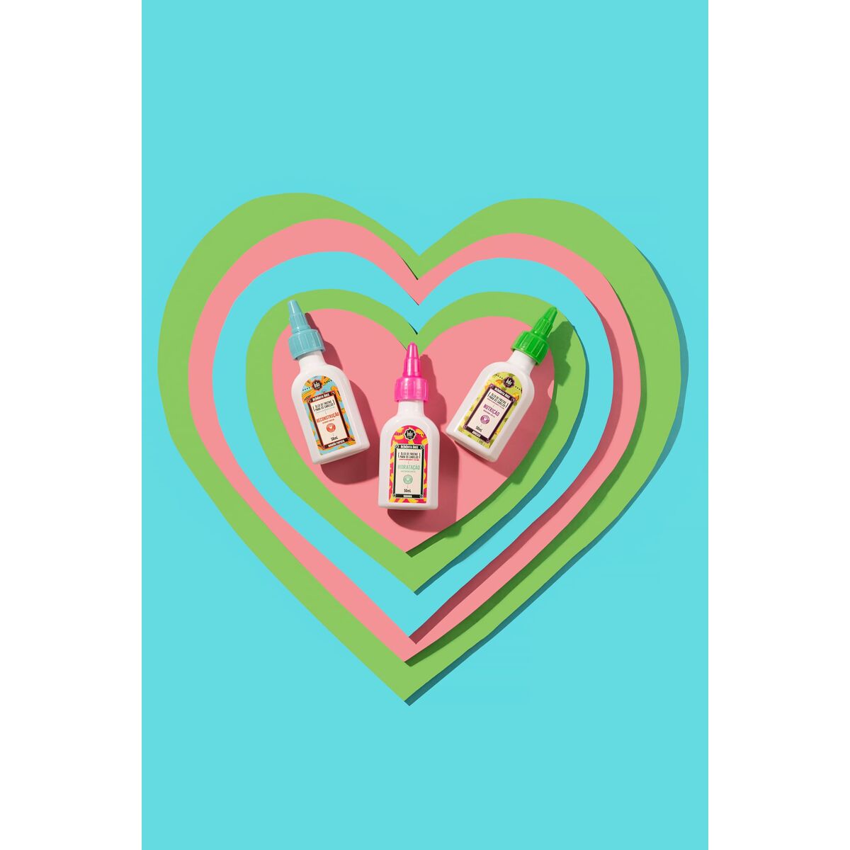 Three colorful adhesive bottles arranged in heart shapes on a teal background, showcasing vibrant packaging.