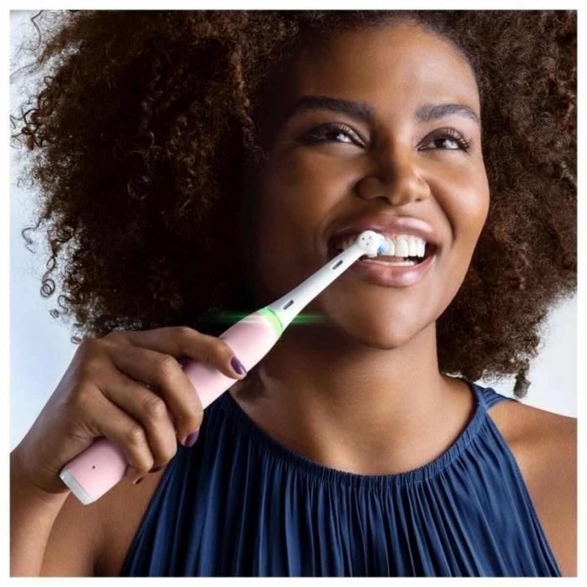 Woman smiling while using the Oral-B io Series 3 electric toothbrush for better oral hygiene.