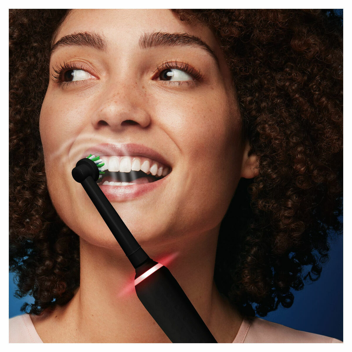 Femme utilisant une brosse à dents électrique Braun Noir avec sourire éclatant et lumière de minuterie.