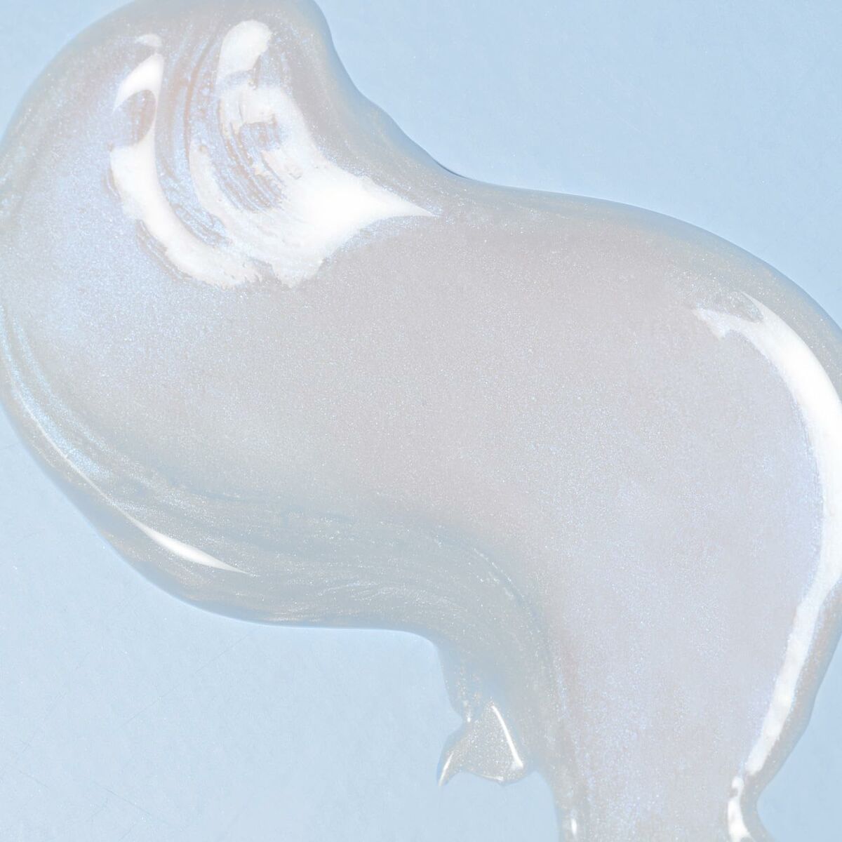 Transparent shimmering lip product swatch on a light blue background.