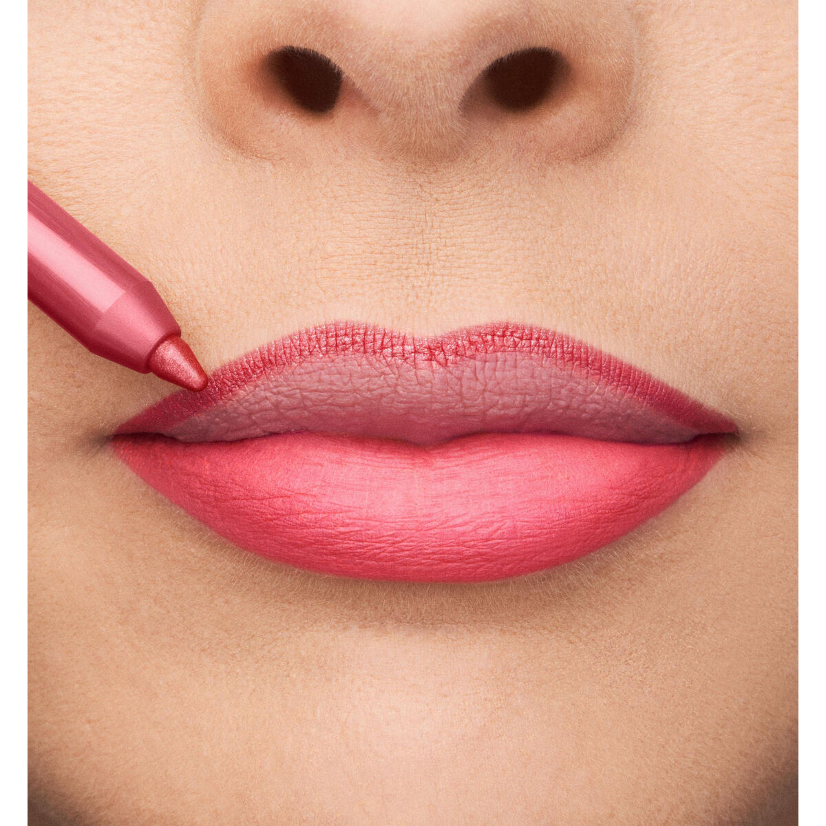 Close-up of lips being outlined with a pink lip pencil, showcasing a vibrant rosy shade.