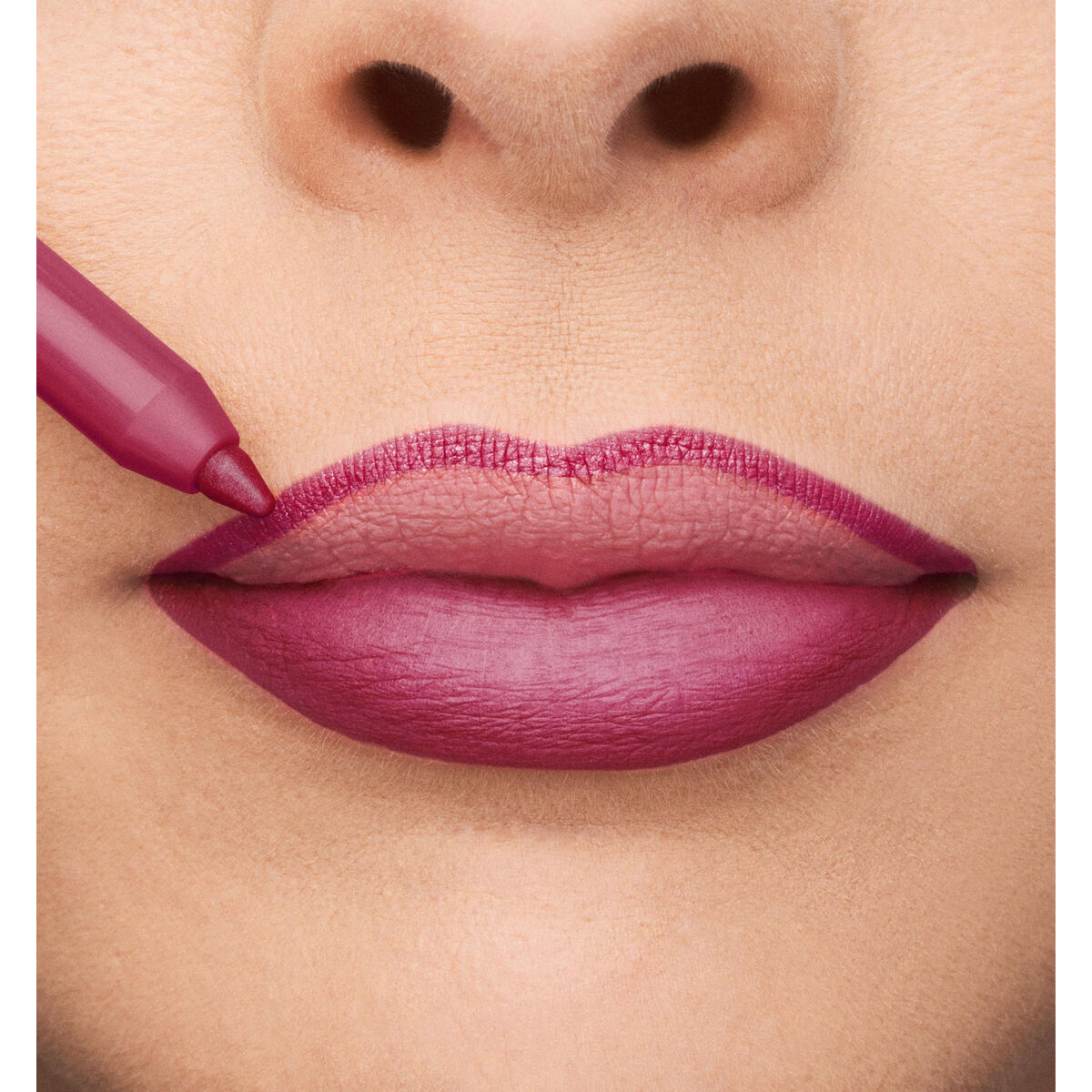 Close-up of lips being lined with a pink lip marker, showcasing a bold lip color for a makeup look.