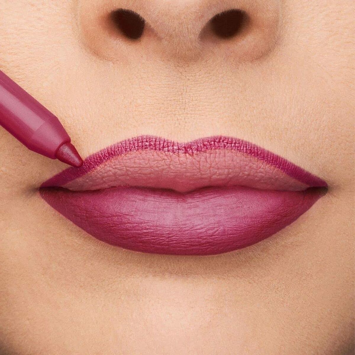Woman applying deep berry lip liner on full lips for a perfect makeup look.