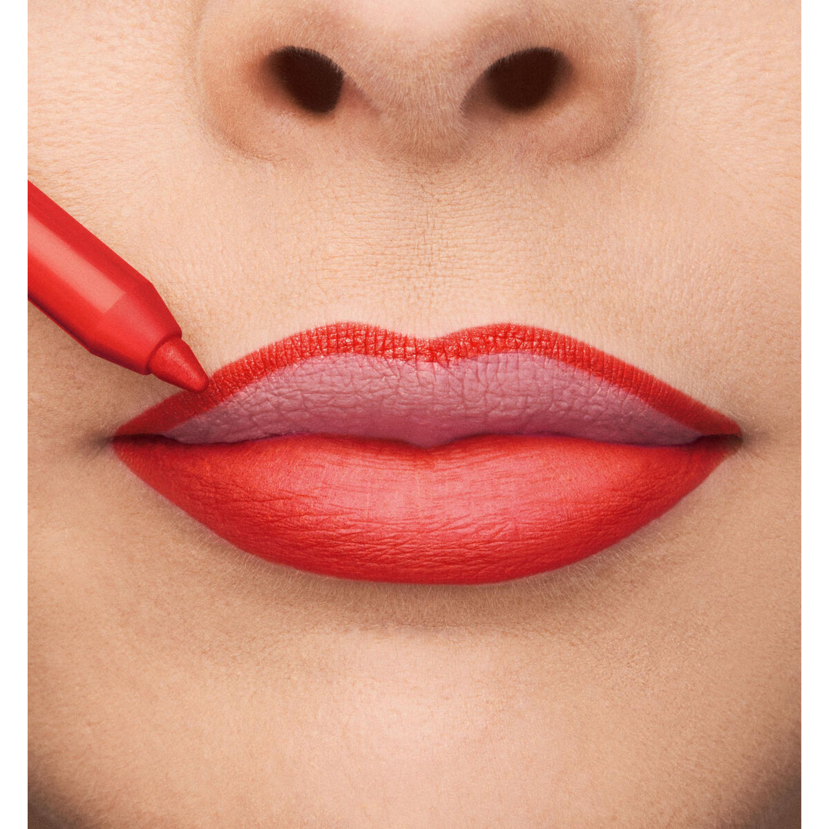 Close-up of lips being lined with a red lip pencil for a bold, vibrant look.