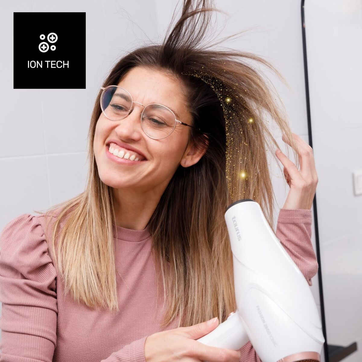 Femme souriante utilisant le sèche-cheveux Taurus FASHION 2600 IO avec technologie ionique pour des cheveux brillants.