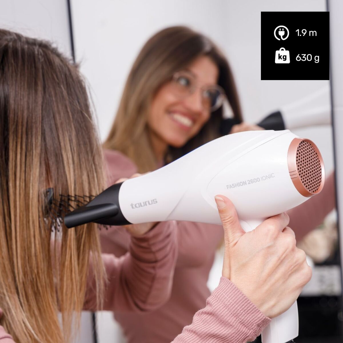 Woman using Taurus FASHION 2600 IO hairdryer in front of a mirror, showcasing its sleek design and features.